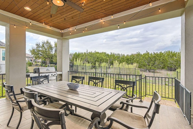 wooden deck with outdoor dining area, area for grilling, ceiling fan, and fence