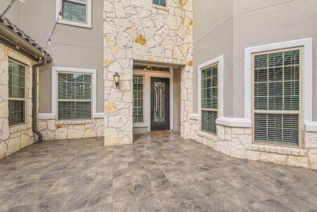 doorway to property with stone siding and stucco siding