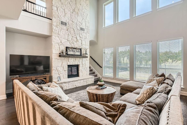 living room featuring plenty of natural light, a fireplace, dark wood-type flooring, and baseboards