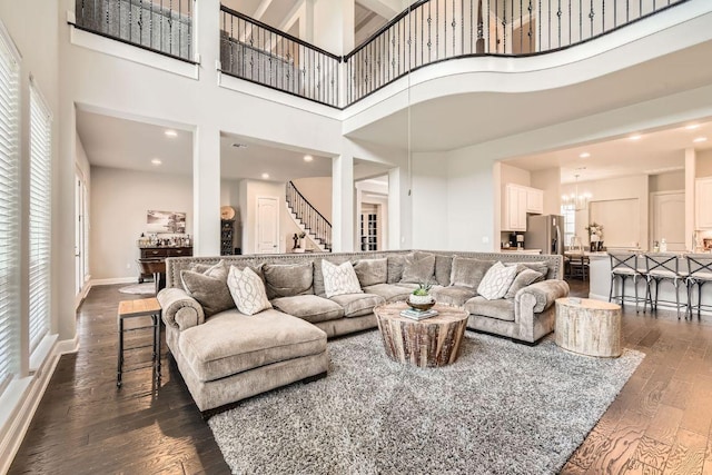 living area featuring dark wood-type flooring, plenty of natural light, baseboards, and a chandelier