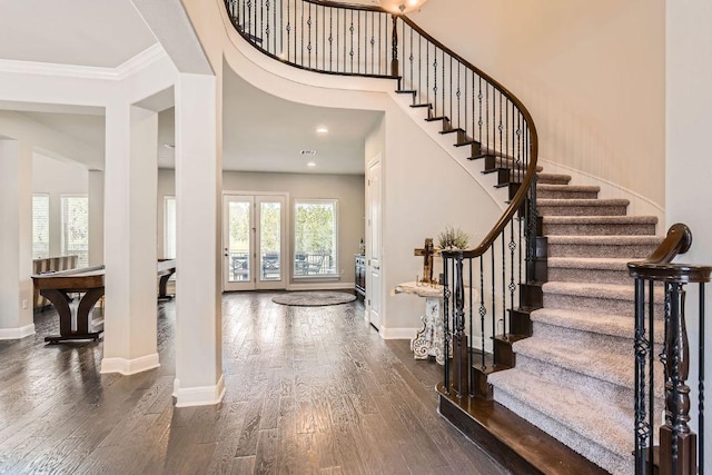 entrance foyer with baseboards, dark wood-type flooring, stairs, and crown molding