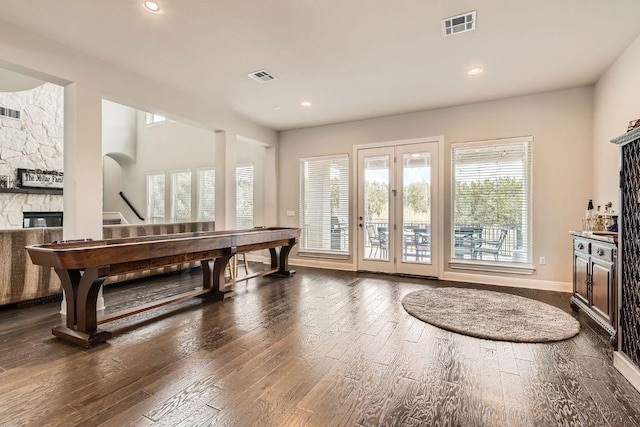 rec room with recessed lighting, visible vents, a stone fireplace, and dark wood finished floors