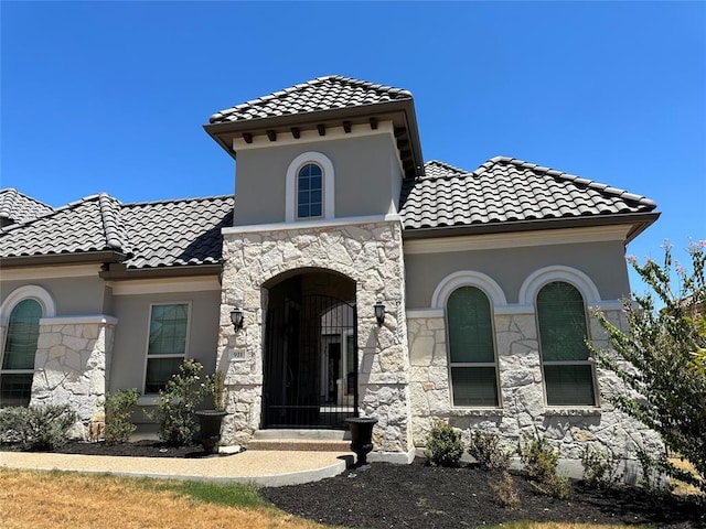 921 Morning Moon Cir, Austin, TX 78732 - mediterranean / spanish-style home with stone siding, a tile roof, and stucco siding