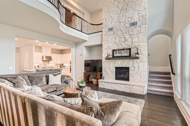 921 Morning Moon Cir, Austin, TX 78732 - living room with a stone fireplace, a high ceiling, dark wood-type flooring, stairway, and baseboards