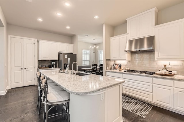 921 Morning Moon Cir, Austin, TX 78732 - kitchen featuring under cabinet range hood, stainless steel appliances, a sink, a center island with sink, and dark wood-style flooring