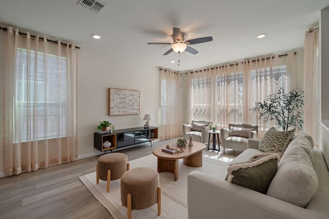 living room featuring visible vents, light wood-style floors, a healthy amount of sunlight, and ceiling fan