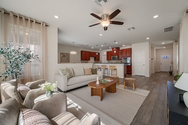 living area with visible vents, ceiling fan, and light wood-style flooring