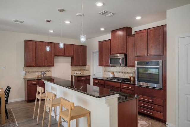 kitchen featuring wood finished floors, visible vents, appliances with stainless steel finishes, and pendant lighting