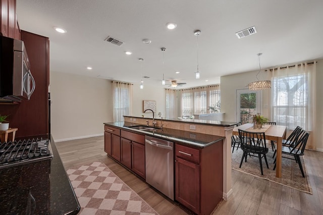 kitchen with visible vents, stainless steel appliances, light wood-style floors, and a sink