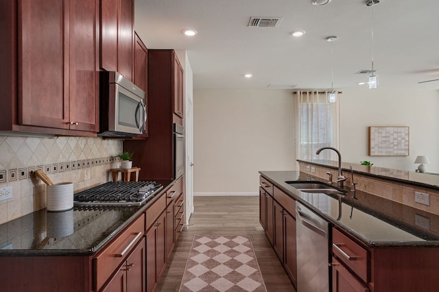 kitchen with visible vents, pendant lighting, a sink, tasteful backsplash, and stainless steel appliances