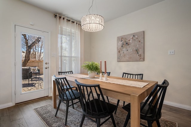 dining space featuring an inviting chandelier, wood finished floors, and baseboards