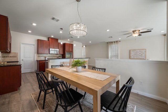 dining space featuring wood finished floors, visible vents, baseboards, recessed lighting, and ceiling fan with notable chandelier