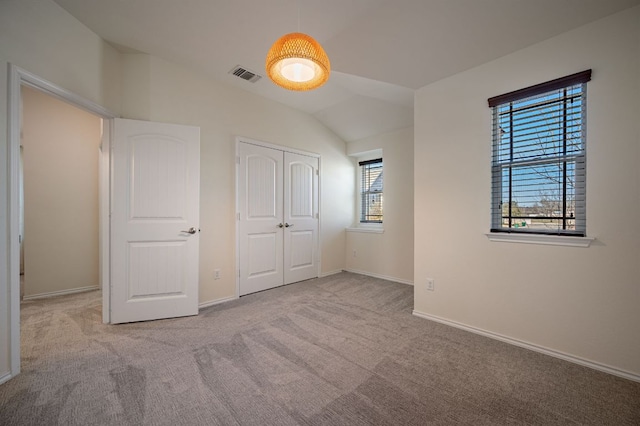 unfurnished bedroom featuring carpet, visible vents, baseboards, lofted ceiling, and a closet