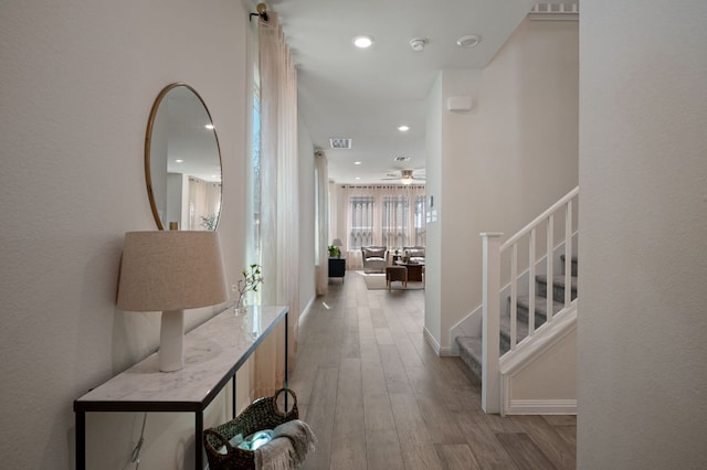 hallway with wood finished floors, visible vents, baseboards, recessed lighting, and stairs