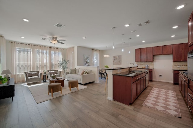 kitchen with a sink, visible vents, light wood-style floors, and open floor plan