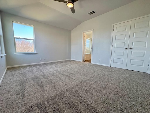 unfurnished bedroom with baseboards, visible vents, vaulted ceiling, a closet, and carpet flooring