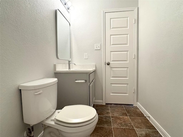 half bathroom featuring vanity, toilet, and baseboards