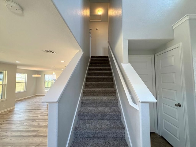 stairway featuring visible vents, baseboards, and wood finished floors