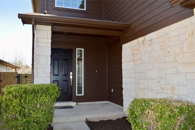 doorway to property featuring covered porch and stone siding