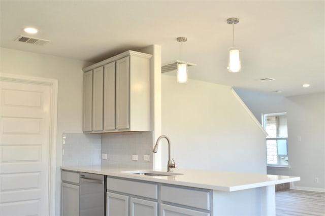 kitchen featuring visible vents, dishwasher, light countertops, decorative backsplash, and a sink