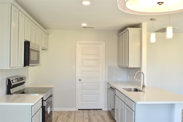 kitchen with visible vents, a sink, stainless steel appliances, light countertops, and light wood-type flooring