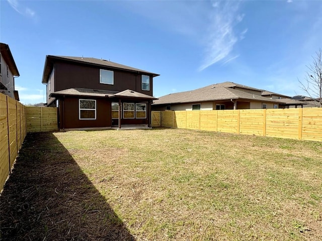 back of house with a yard and a fenced backyard