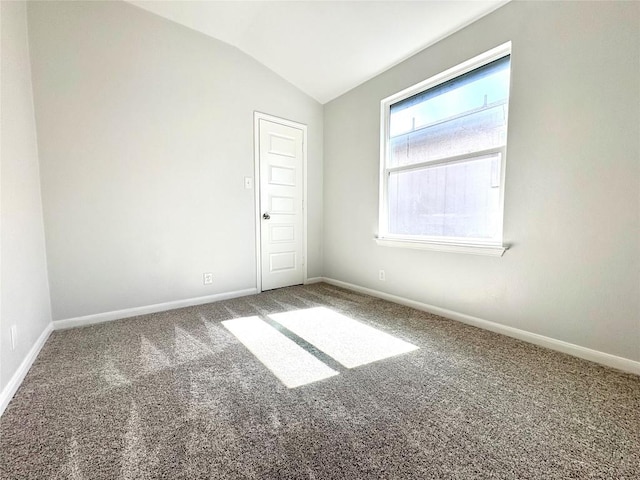 carpeted spare room with baseboards and vaulted ceiling