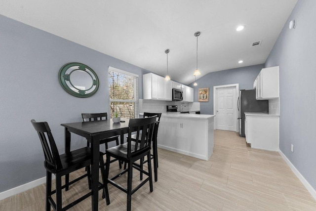 dining room with visible vents, baseboards, lofted ceiling, recessed lighting, and light wood-style flooring