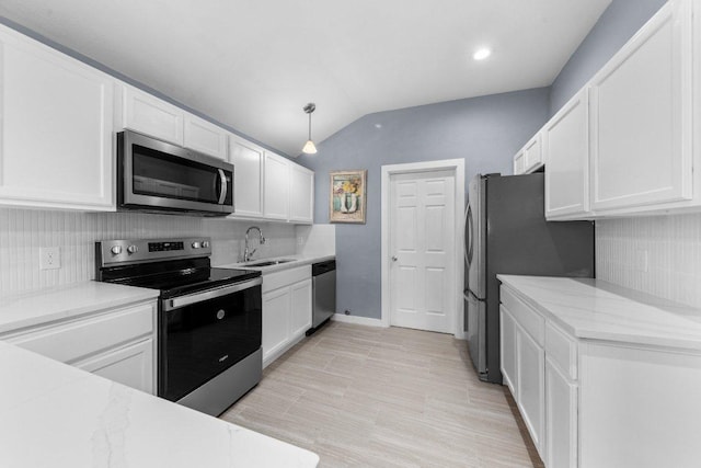 kitchen with a sink, white cabinetry, appliances with stainless steel finishes, decorative backsplash, and lofted ceiling