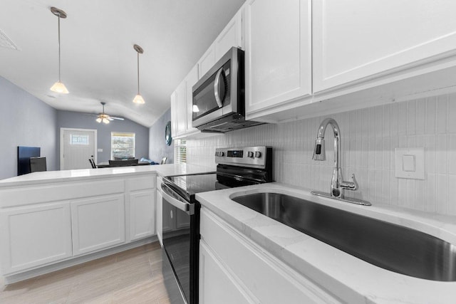 kitchen with a sink, stainless steel appliances, pendant lighting, and white cabinetry