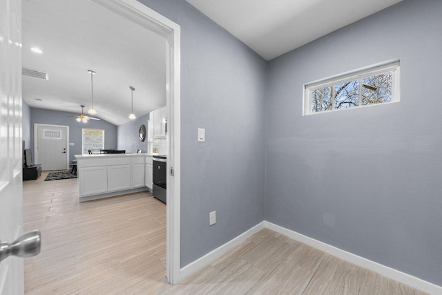 kitchen featuring white cabinetry, light wood-style flooring, baseboards, and a wealth of natural light