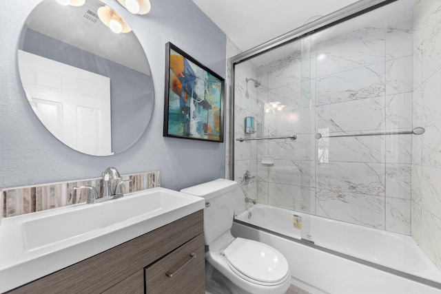 bathroom with shower / bath combination with glass door, toilet, vanity, and a textured wall