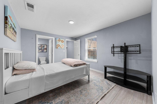 bedroom with visible vents, ensuite bath, and baseboards