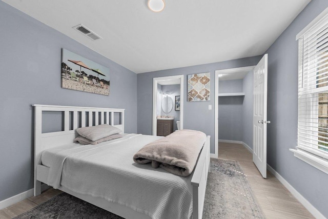 bedroom with visible vents, baseboards, light wood-style flooring, and a spacious closet