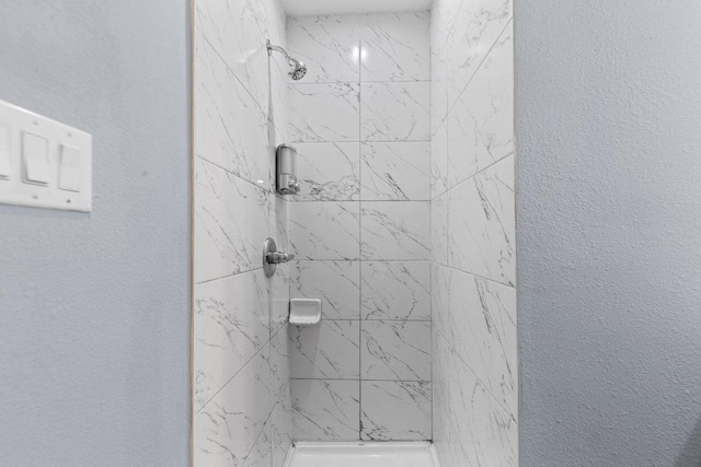 full bath with a shower stall and a textured wall