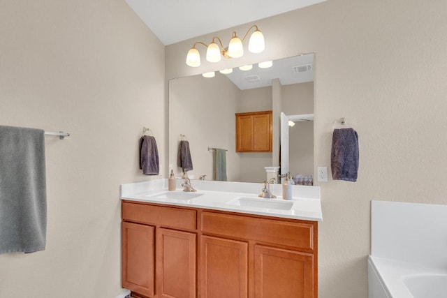 bathroom with double vanity, visible vents, a tub, and a sink