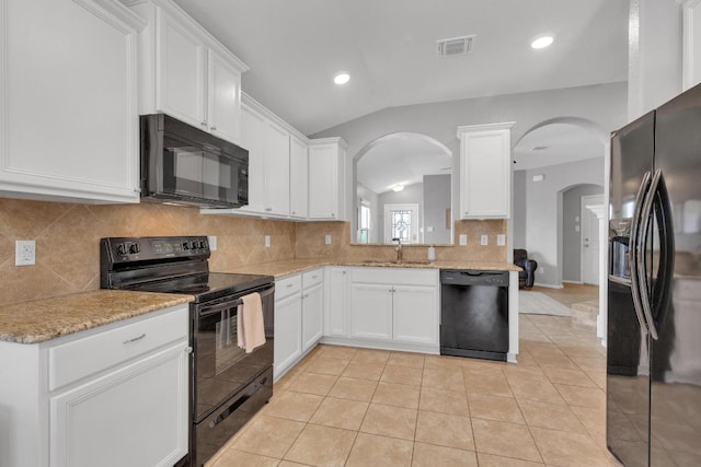 kitchen with visible vents, black appliances, a sink, arched walkways, and vaulted ceiling