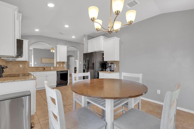 dining area featuring light tile patterned floors, visible vents, lofted ceiling, arched walkways, and ceiling fan with notable chandelier