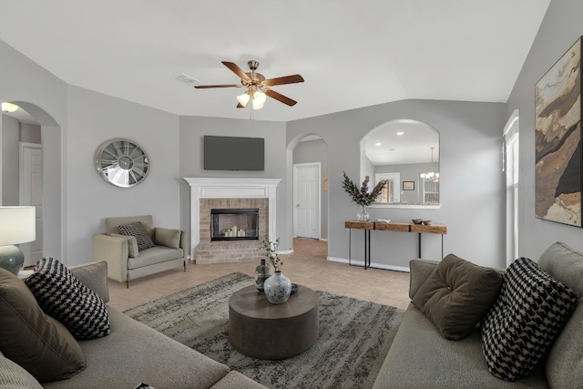 living area with visible vents, a ceiling fan, arched walkways, a fireplace, and baseboards