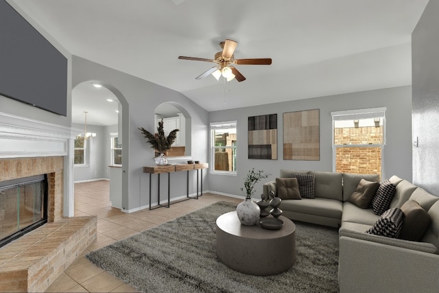 living area with light tile patterned flooring, plenty of natural light, a fireplace with raised hearth, and a ceiling fan