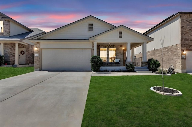 view of front of house featuring driveway, a yard, an attached garage, covered porch, and brick siding