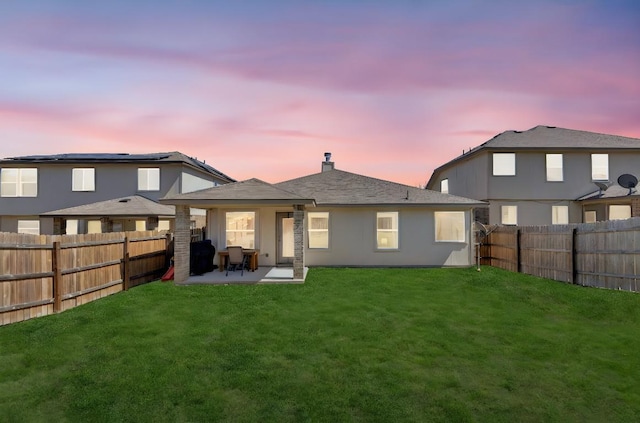 back of house with a yard, a fenced backyard, and a patio area