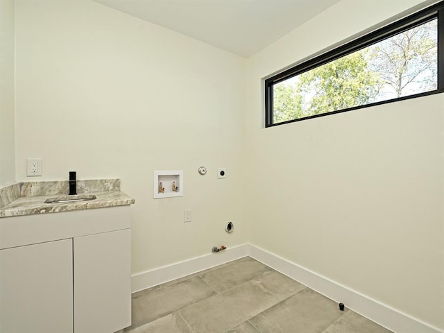 clothes washing area featuring electric dryer hookup, a sink, hookup for a gas dryer, cabinet space, and baseboards