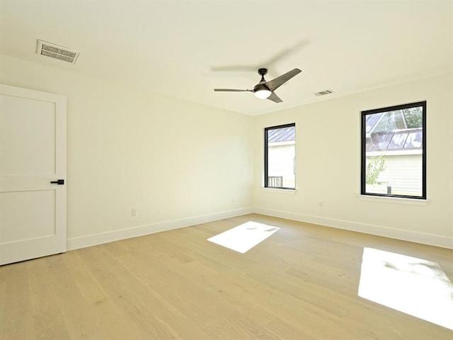 unfurnished room featuring a healthy amount of sunlight, visible vents, and light wood finished floors