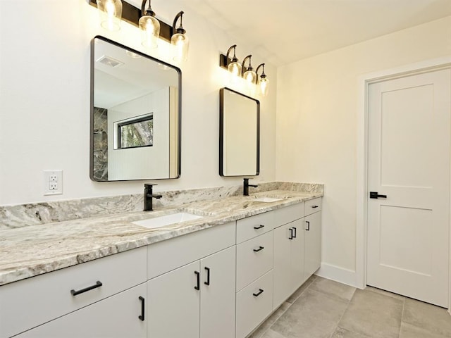 full bath with a sink, visible vents, baseboards, and double vanity