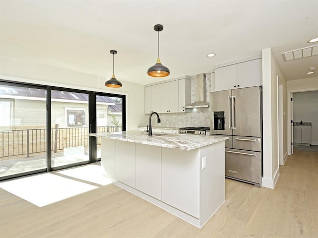 kitchen with visible vents, a sink, high quality fridge, wall chimney exhaust hood, and range