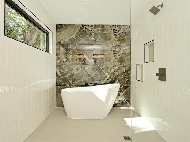 bathroom featuring tile patterned flooring, tile walls, a freestanding bath, and walk in shower