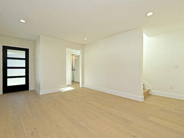 spare room featuring recessed lighting, baseboards, light wood-style floors, and stairs