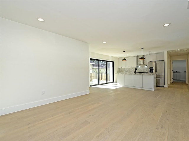 unfurnished living room with recessed lighting, baseboards, and light wood finished floors