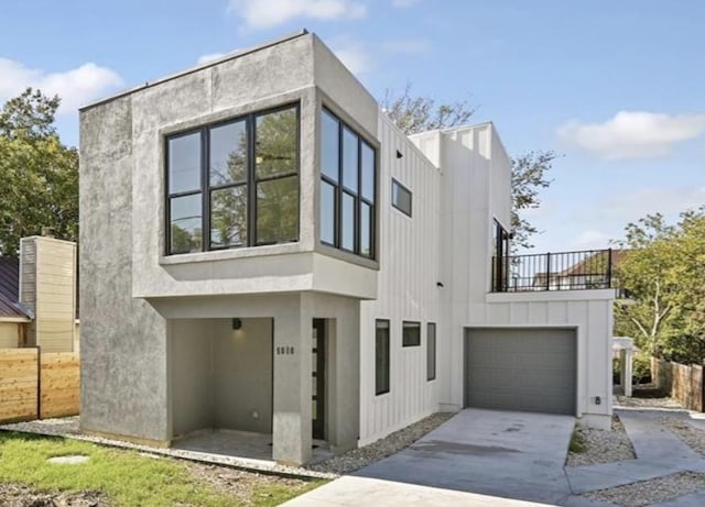 contemporary home featuring a garage, stucco siding, driveway, and fence